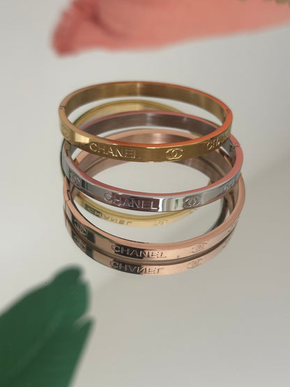 Four Swarovski branded bangles stacked on a light gray background
